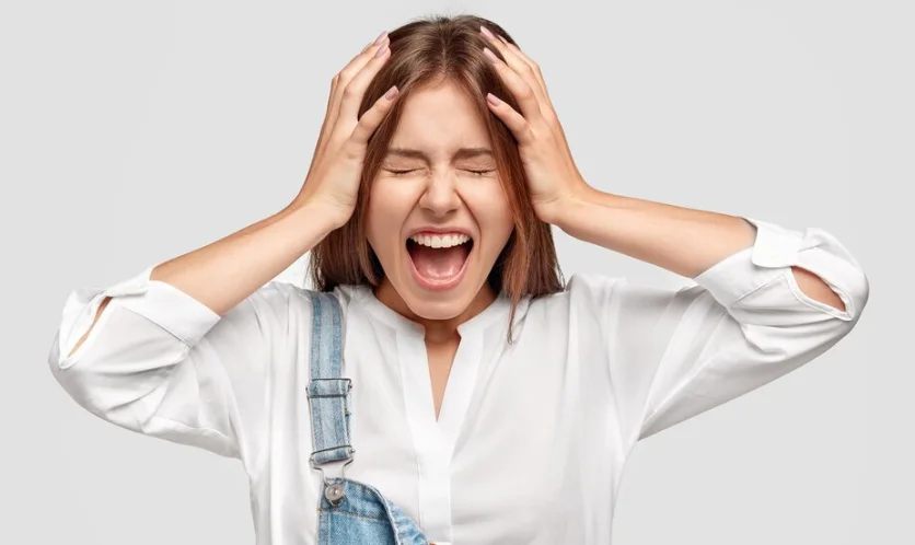 девушка с истерикой кричит и держится за голову